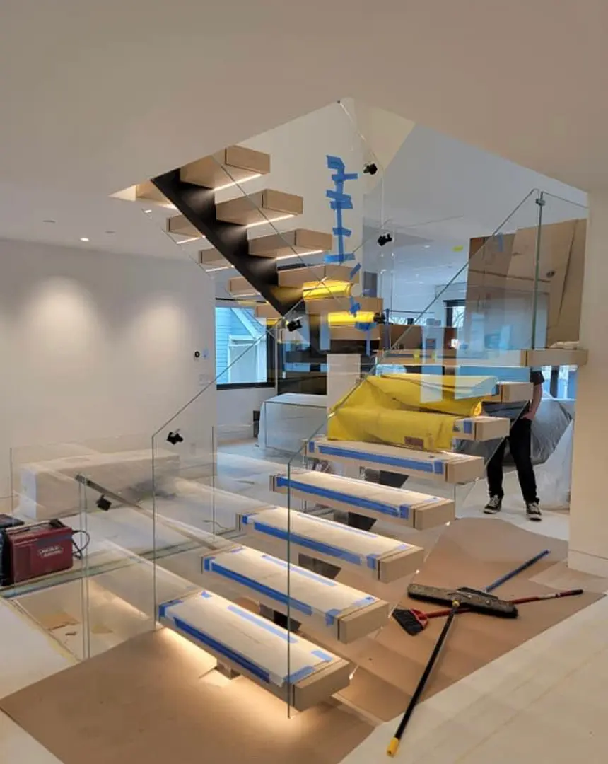 Frameless glass railing panels installed along a floating staircase by Glass Squad