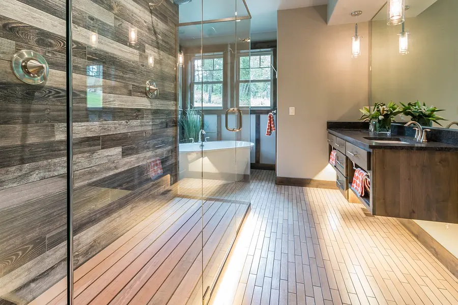 Spotless full-height glass shower wall beside a freestanding tub in a spa-style bathroom