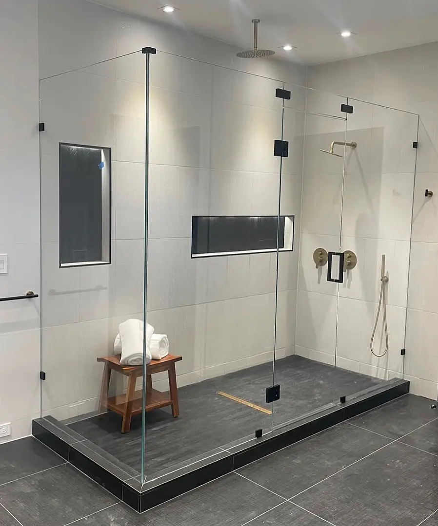 Floor-to-ceiling frameless glass steam shower enclosure with matte black clamps, installed by Glass Squad